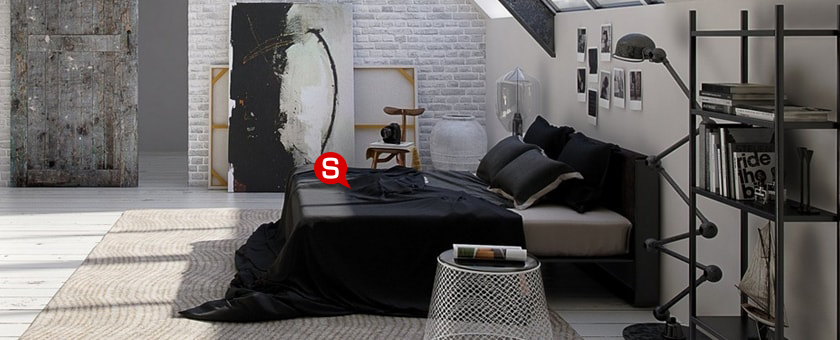 Ein geräumiges Schlafzimmer im industriellen Einrichtungsstil mit weißen Wänden und einem großen, schwarzen Polsterbett. Neben dem Bett steht eine stilvolle Stehlampe und ein Regal aus Metall.