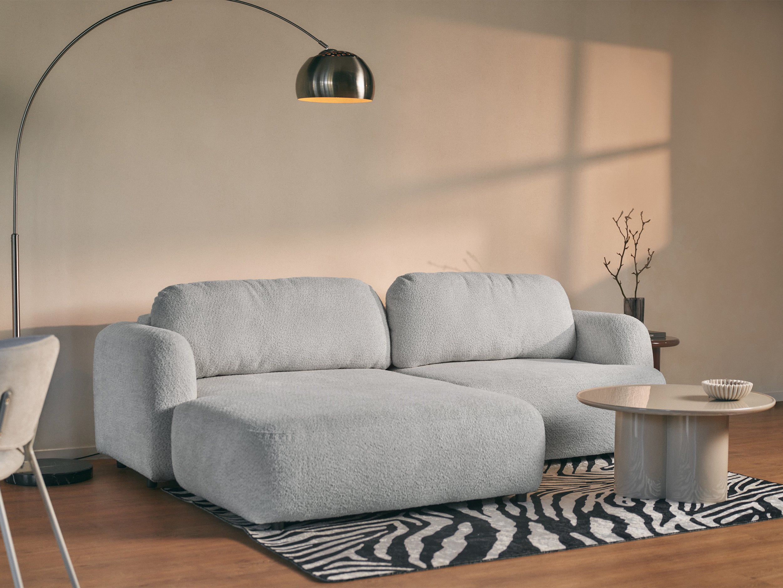Ecksofa mit Schlaffunktion Tvoya, L-förmig, linksseitig, hellgrauer Bouclé-Stoff