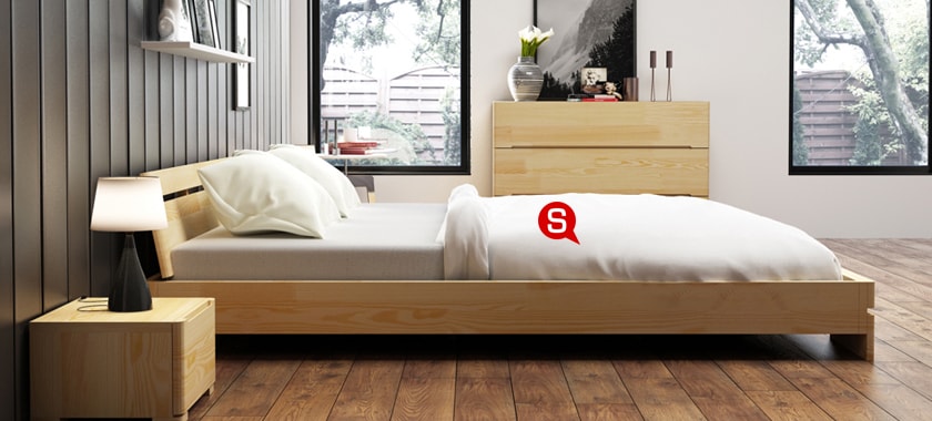Ein gemütliches Schlafzimmer mit einem großen Holzbett. Nachttisch und Kommode aus hellem Holz runden das Gesamtbild perfekt ab.
